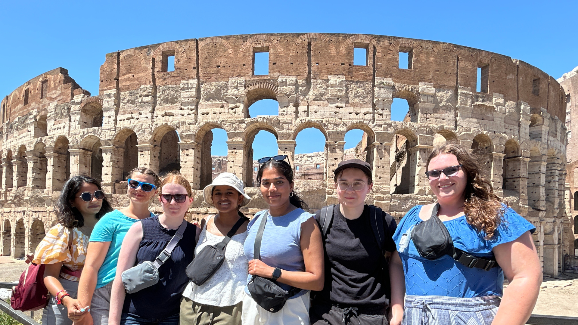 Seven students standing in front of the Colosseum in Rome. 