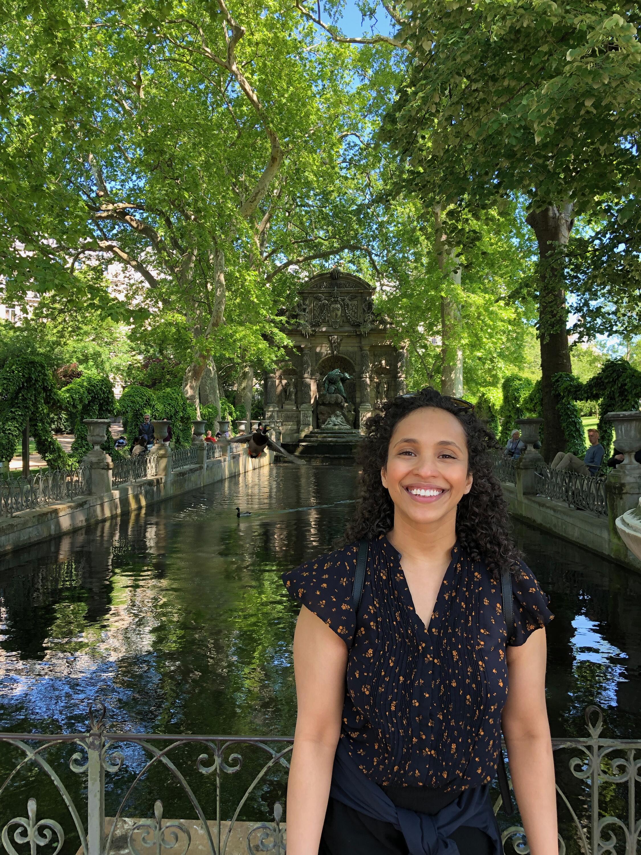 Nasra Smith in front of a fountain surrounded by trees