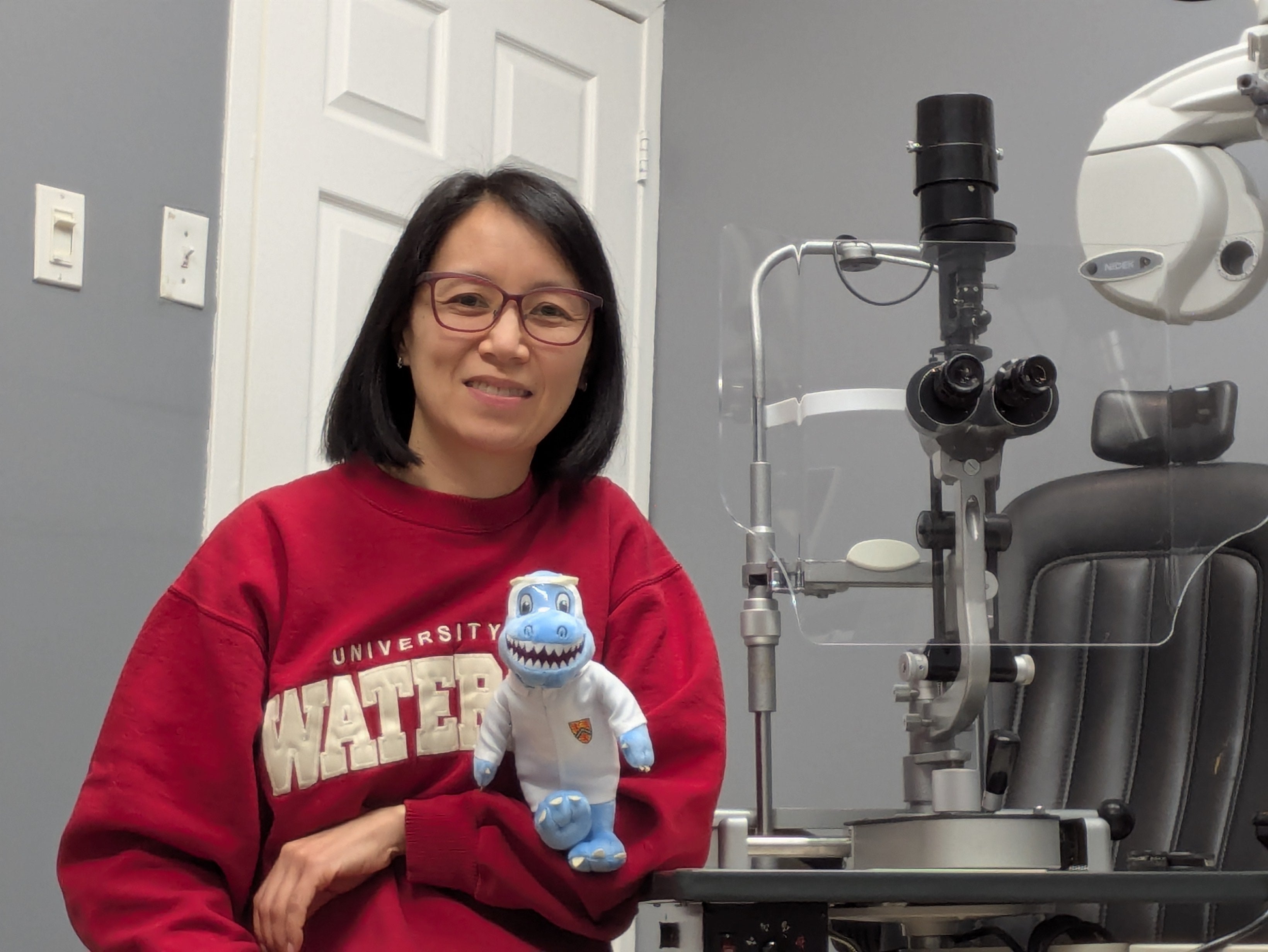 Jane Tzeng holding a stuffed Cobalt in an optometry clinic room