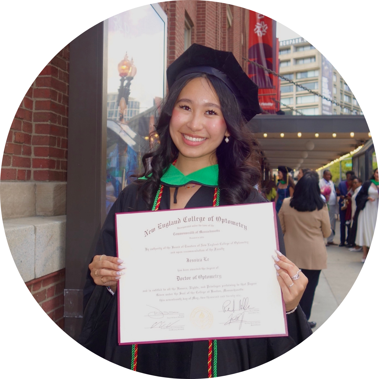 Jessica Le holding her diploma and wearing convocation robes