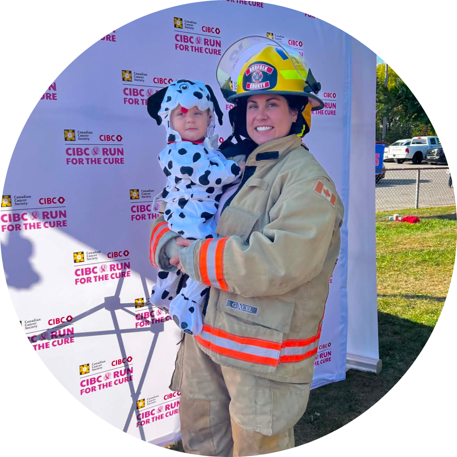 Kate Petrella in her firefighter suit, holding a child dressed like a dalmatian puppy