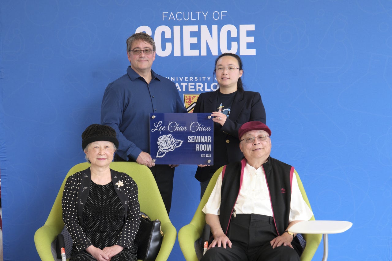 The Lee family holding up a sign that says "Lee Chan Chiou seminar room".