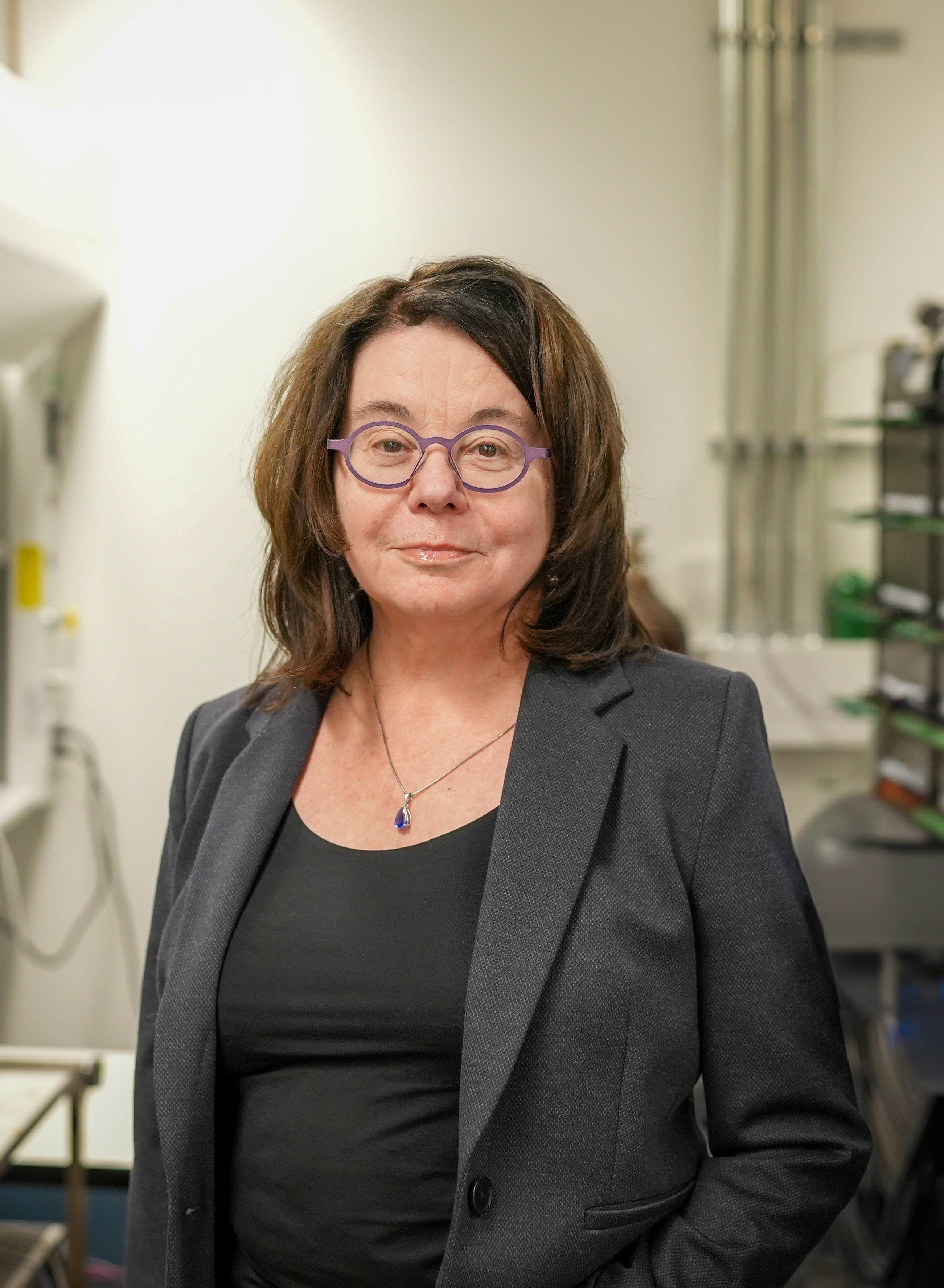 Nazar is smiling into the camera. She's wearing glasses and black blazer. 