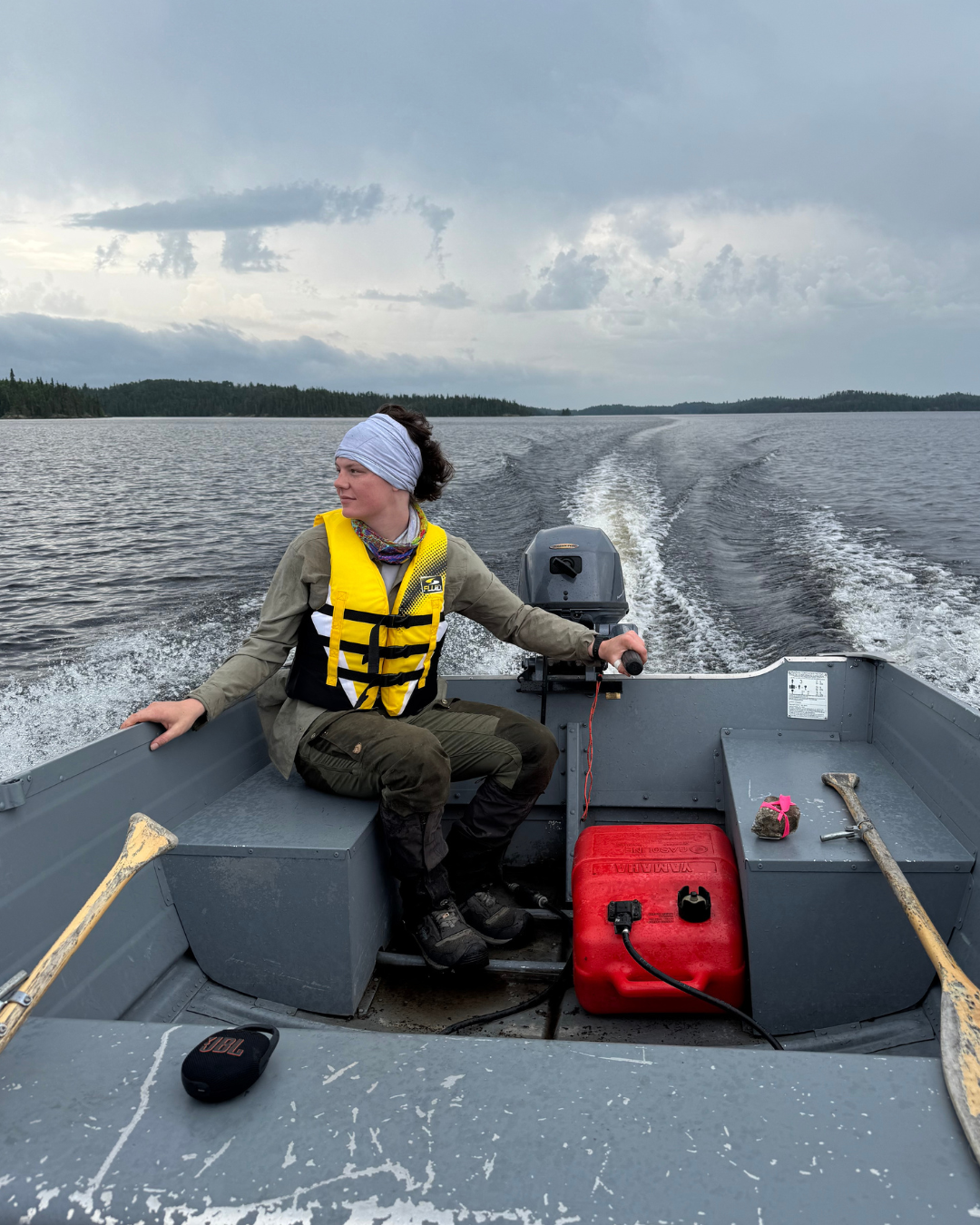Nathalie steering a small fishing boat on a lake.