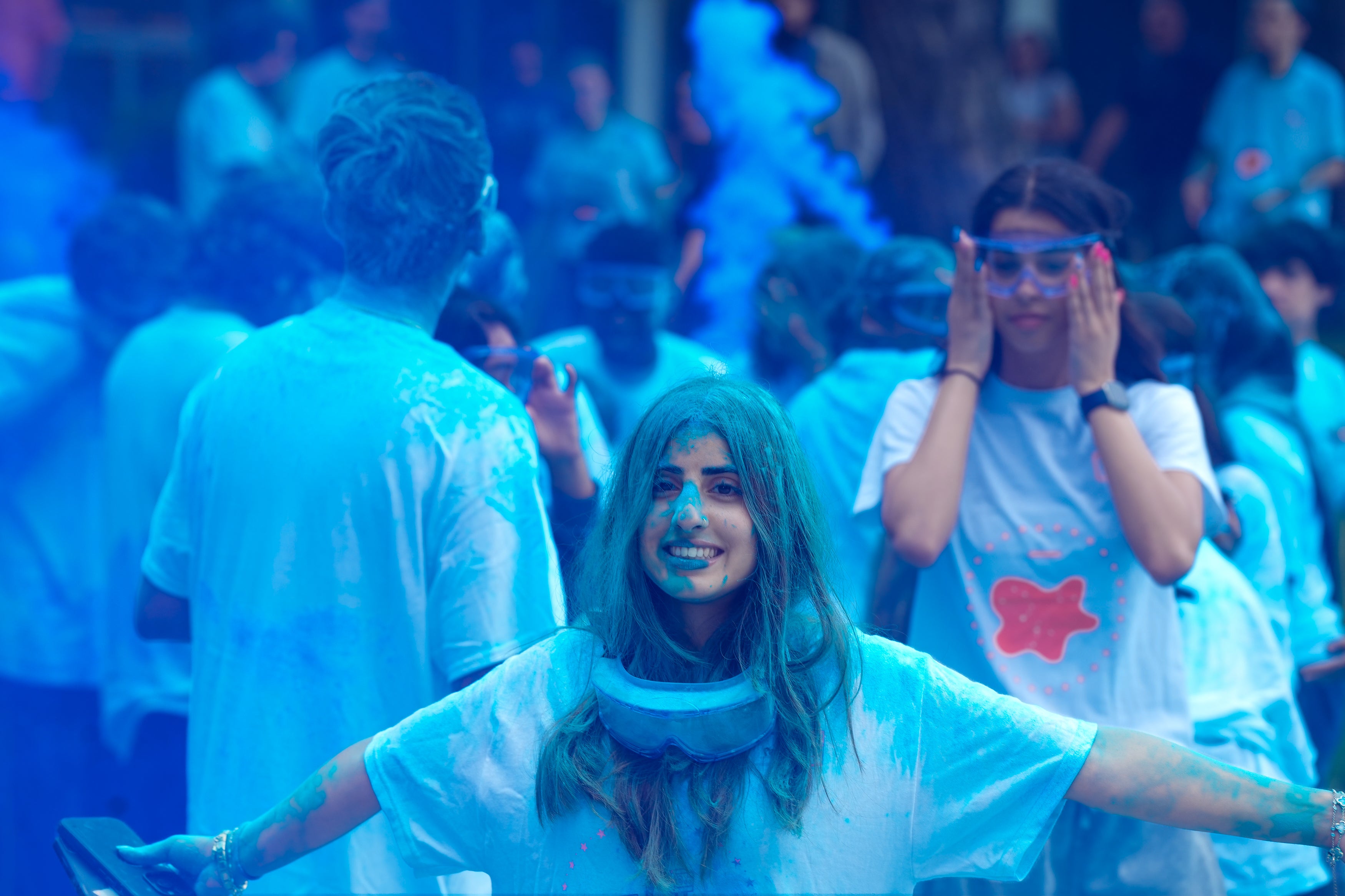 A girl wearing lab goggles covered in blue powder