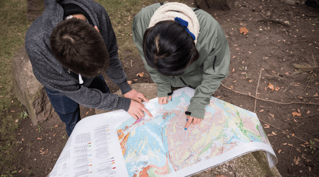 Two students navigating a map outdoors.