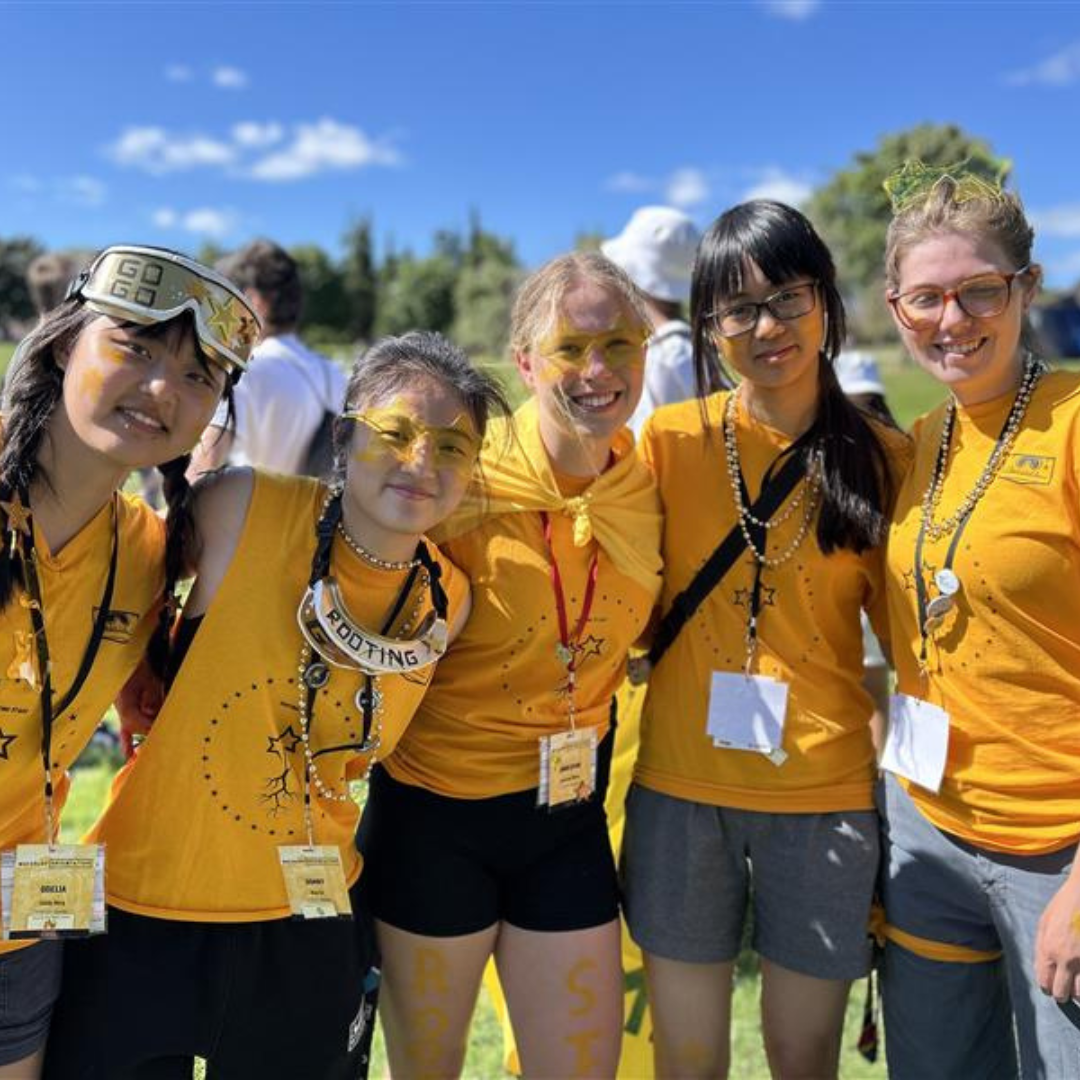 Five students wearing yellow at an orientation event. 