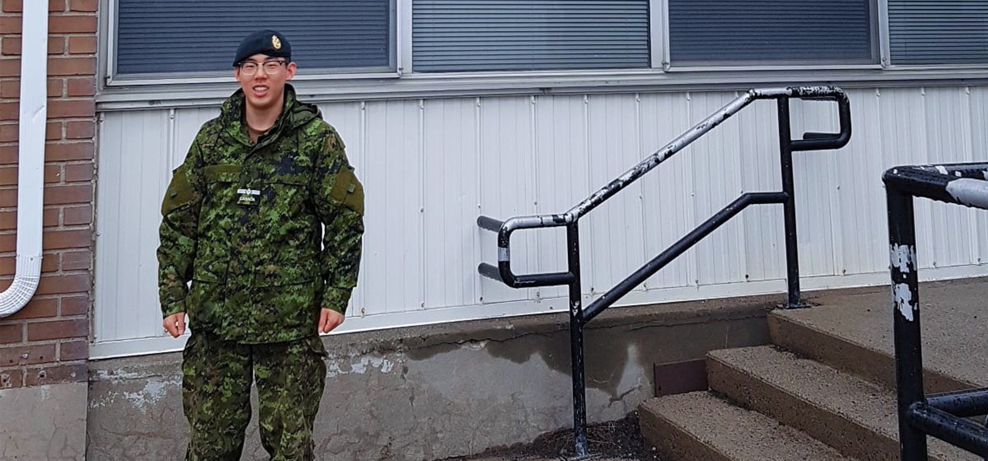 Sean standing outside the medical clinic in military attire
