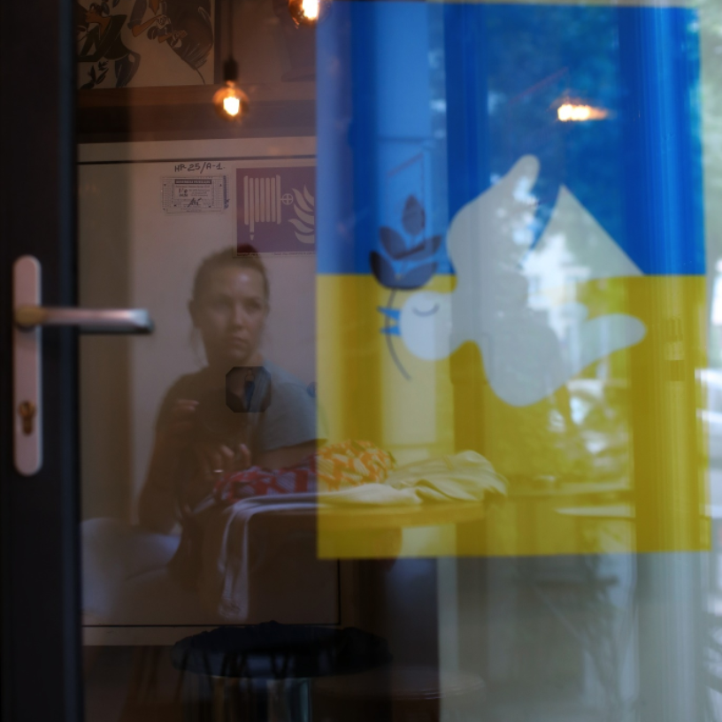 Olga Shmaidenko's reflection beside a Ukrainian flag