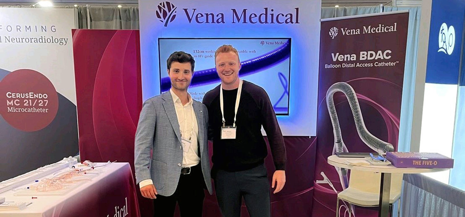 Two males in suits standing in front of the Vena Medical booth.
