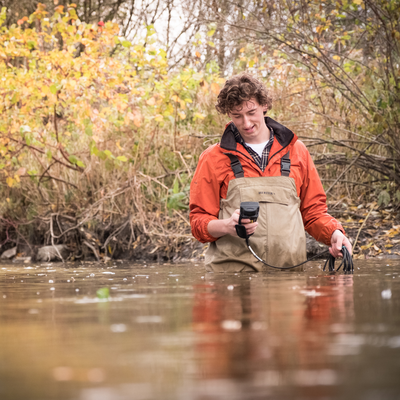 An Earth sciences student standing in a river for research.