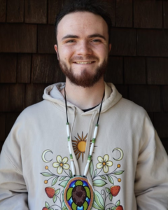 Ethan Gardner wearing a beige sweatshirt with Indigenous artwork. 