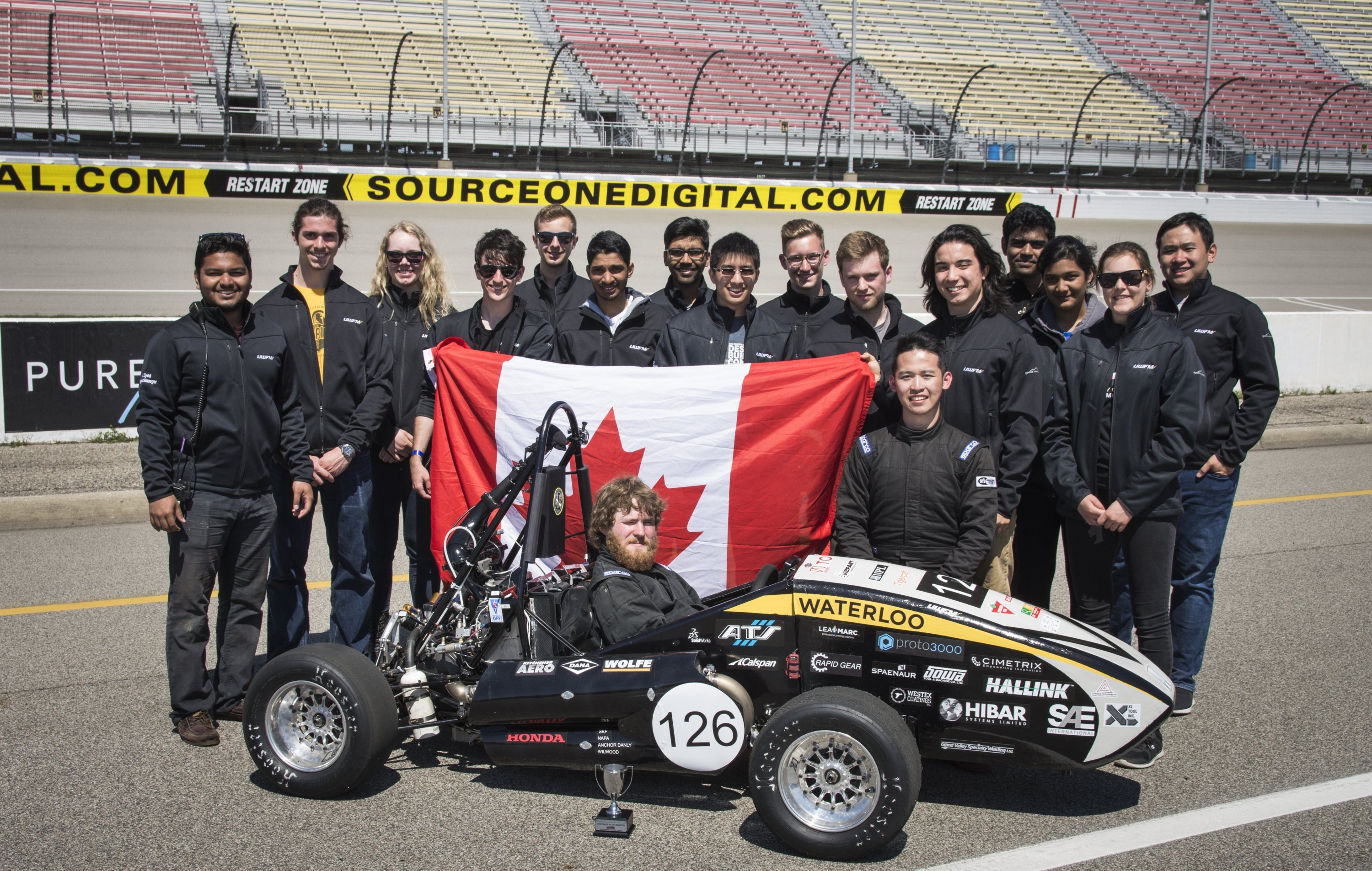 UW Formula Motorspots Team with their car adn showing their canadian pride with the flag!