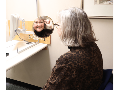 Old lady wearing glasses looking in the mirror