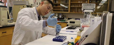 Lab member in lab coat pipetting.