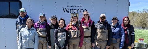 Servos group photo. A van behind everyone with the University of Waterloo logo.