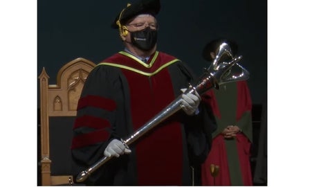 Mark Servos leads the convocation procession as the mace-bearer. 