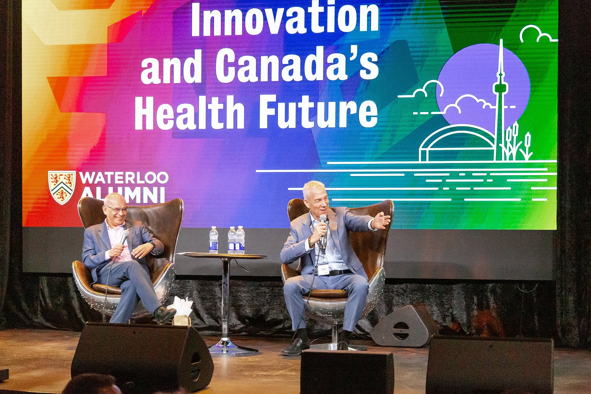 Vivek gesturing on stage with a large screen announcing Innovation and Canada's Health Futures