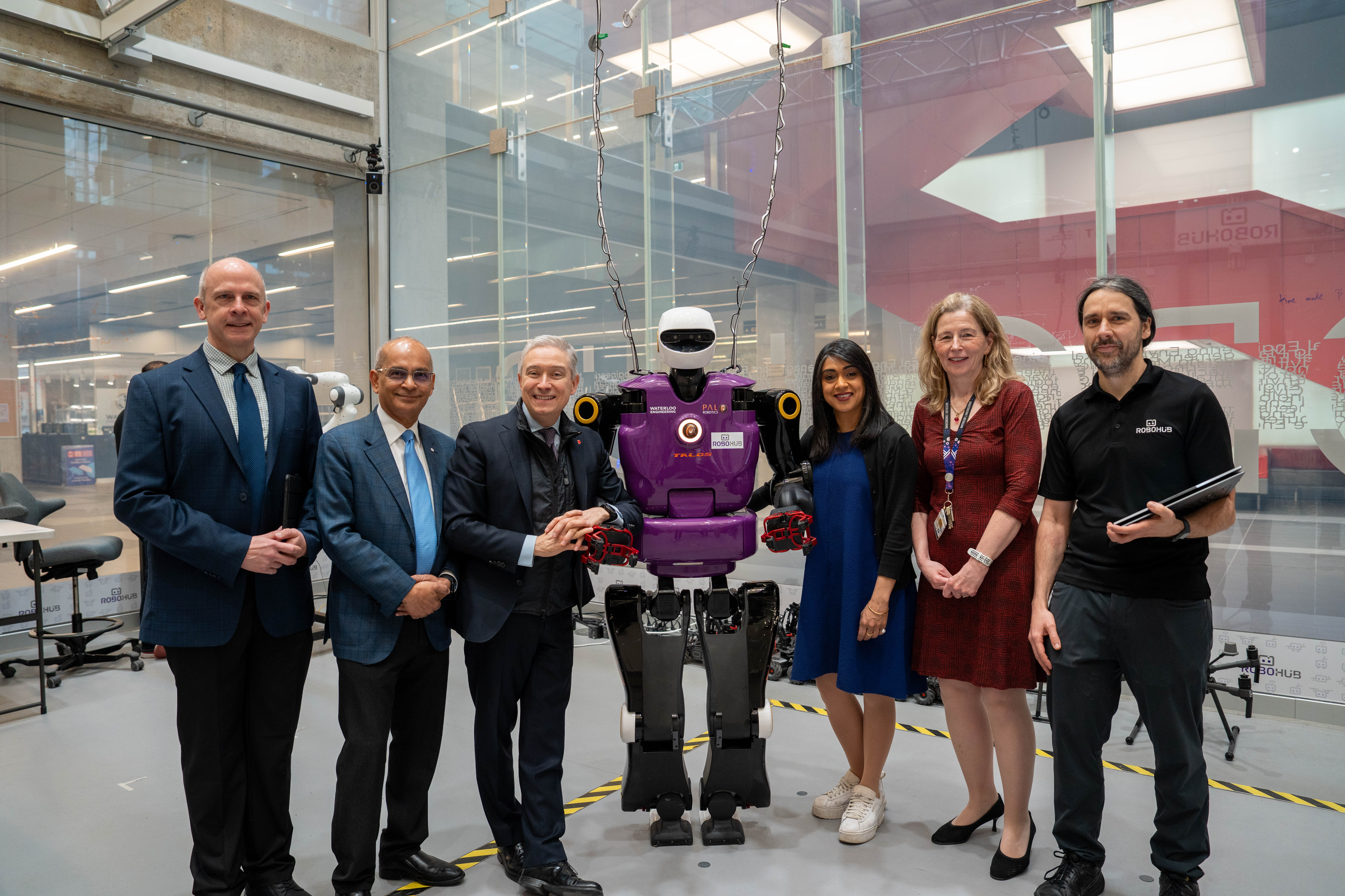 A group of people posing with a robot