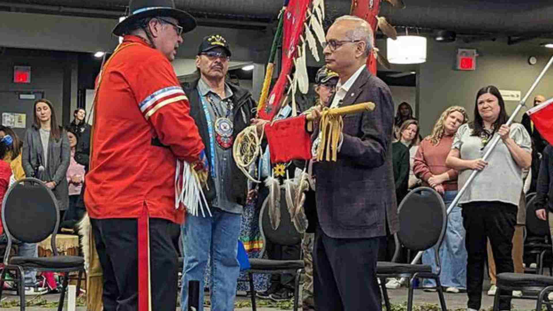 Vivek holding an eagle staff in front of an indigenous elder