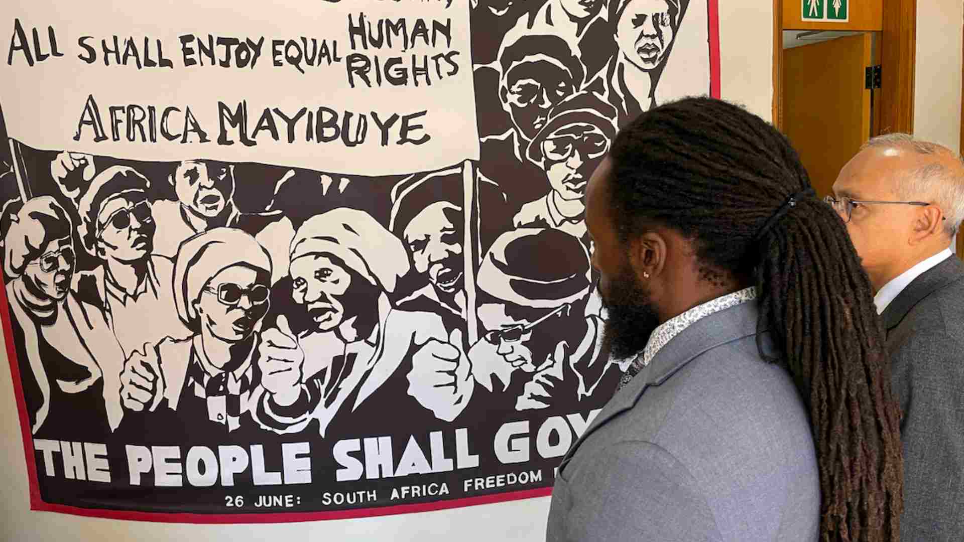 two men looking a south african mural about justice