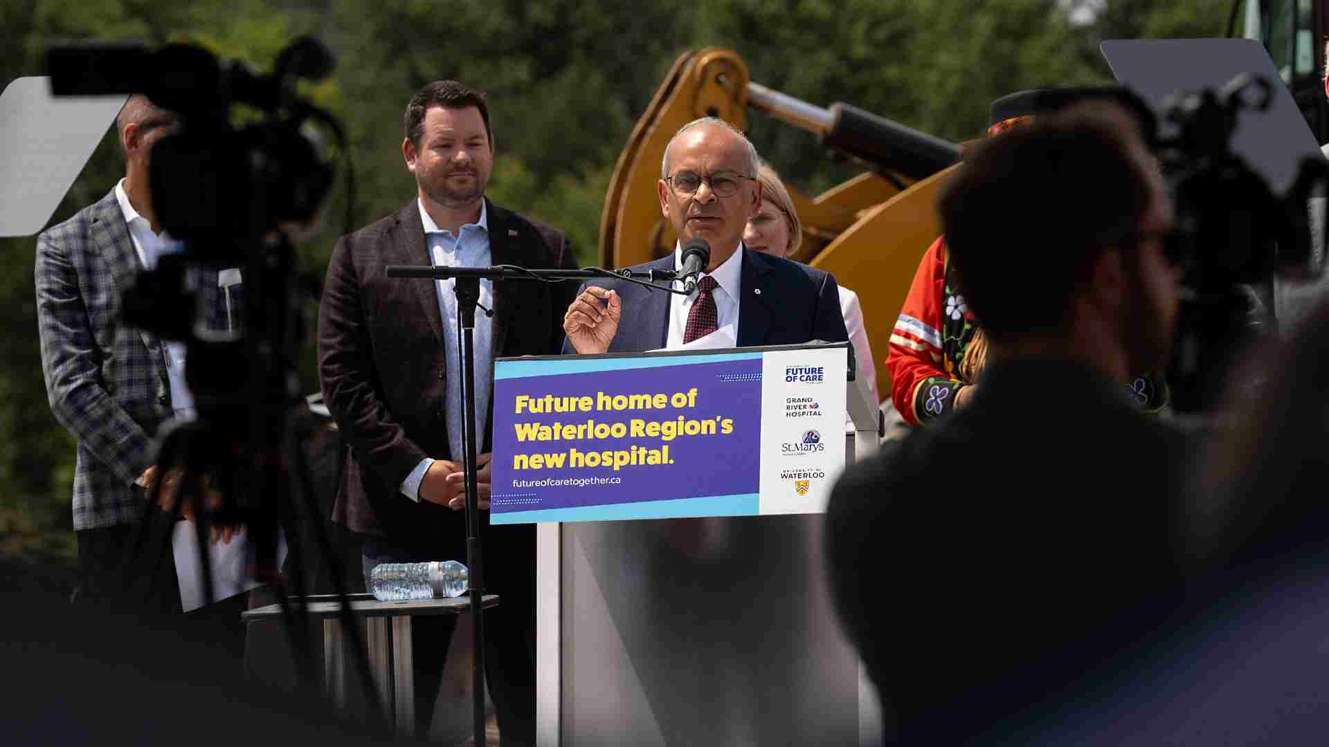 Vivek at a podium with a poster announcing the hospital