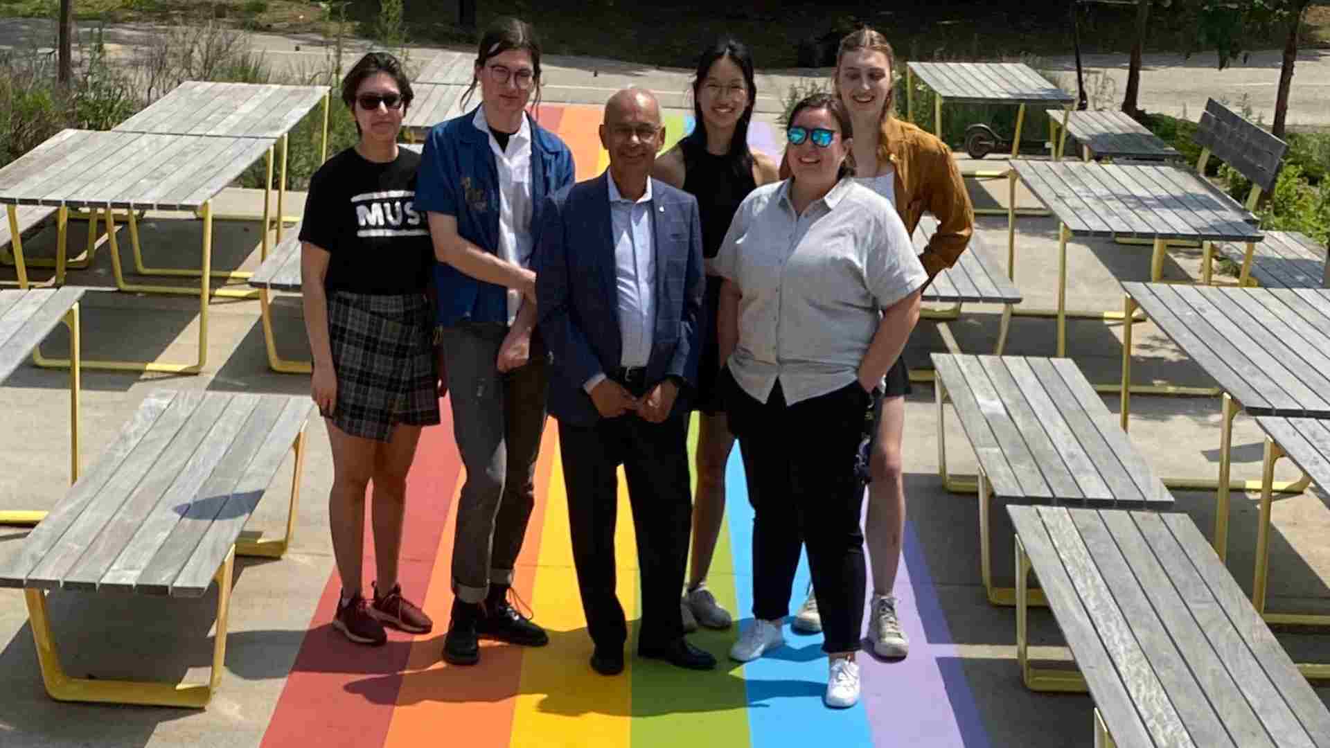 Vivek and students on a pride flag painted walkway
