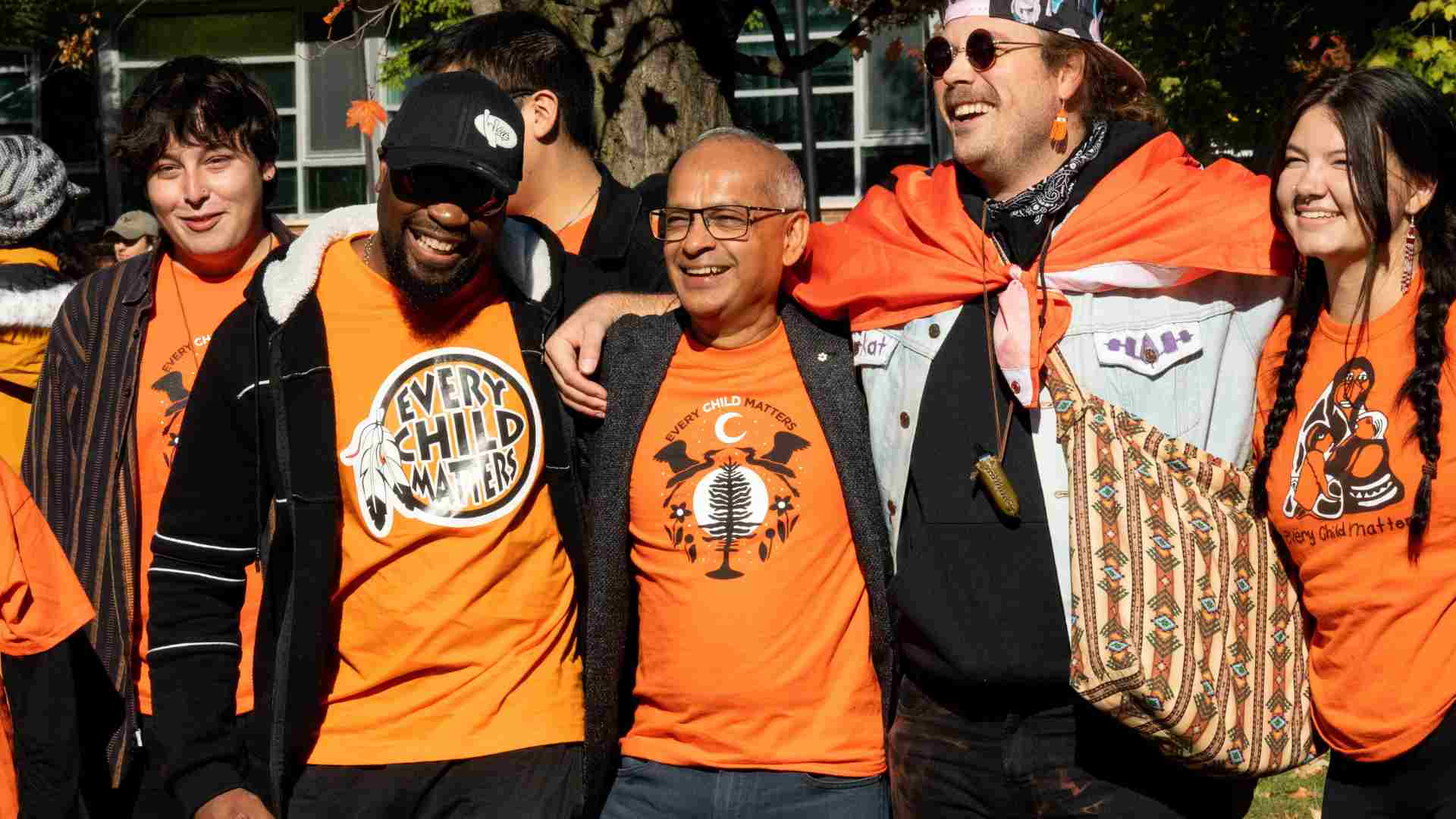 Vivek in an orange shirt amongst students wearing orange shirts