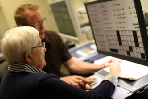 Two people view a crossword puzzle on a CCTV screen