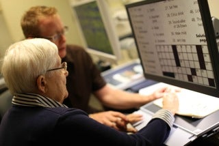 Two people view a crossword puzzle on a CCTV screeen