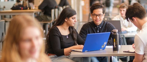Students working on a blue laptop