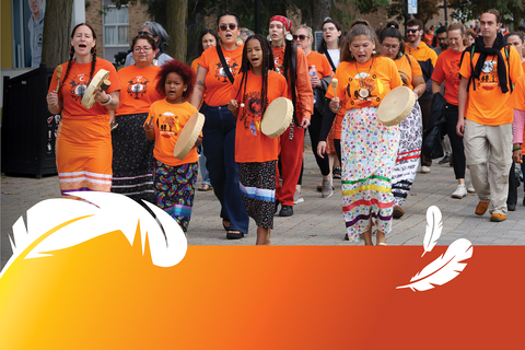 Waterloo Indigenous community wearing wearing orange t-shirts, holding Indigenous hand drum and walking down Ring Road