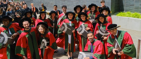 Waterloo PhD graduates celebrating at convocation with their diplomas and regalia