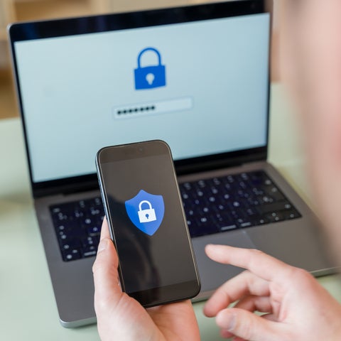 Guy holding a phone in front of a laptop for two-factor authentication security