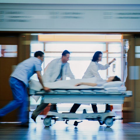 Out of focus shot of medical professionals wheeling a hospital bed down a hall with a patient 