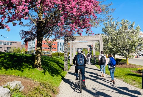 People walking and riding a bike to campus
