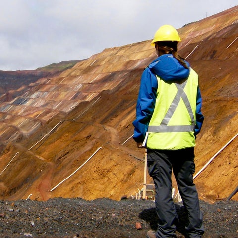 Man wearing safety gear standing on a cliff overlook a hill