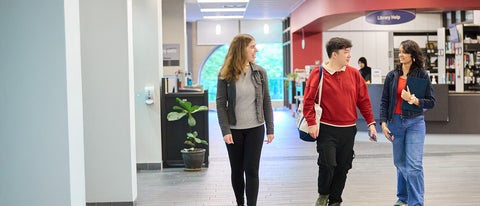 Three students walking in the Dana Porter Library