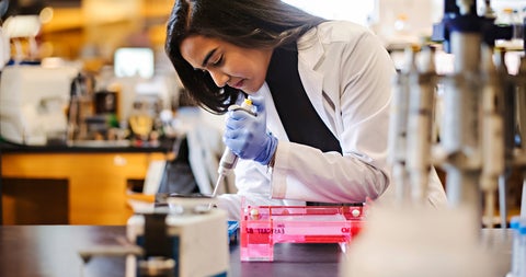 Student in a lab coat using a pipette