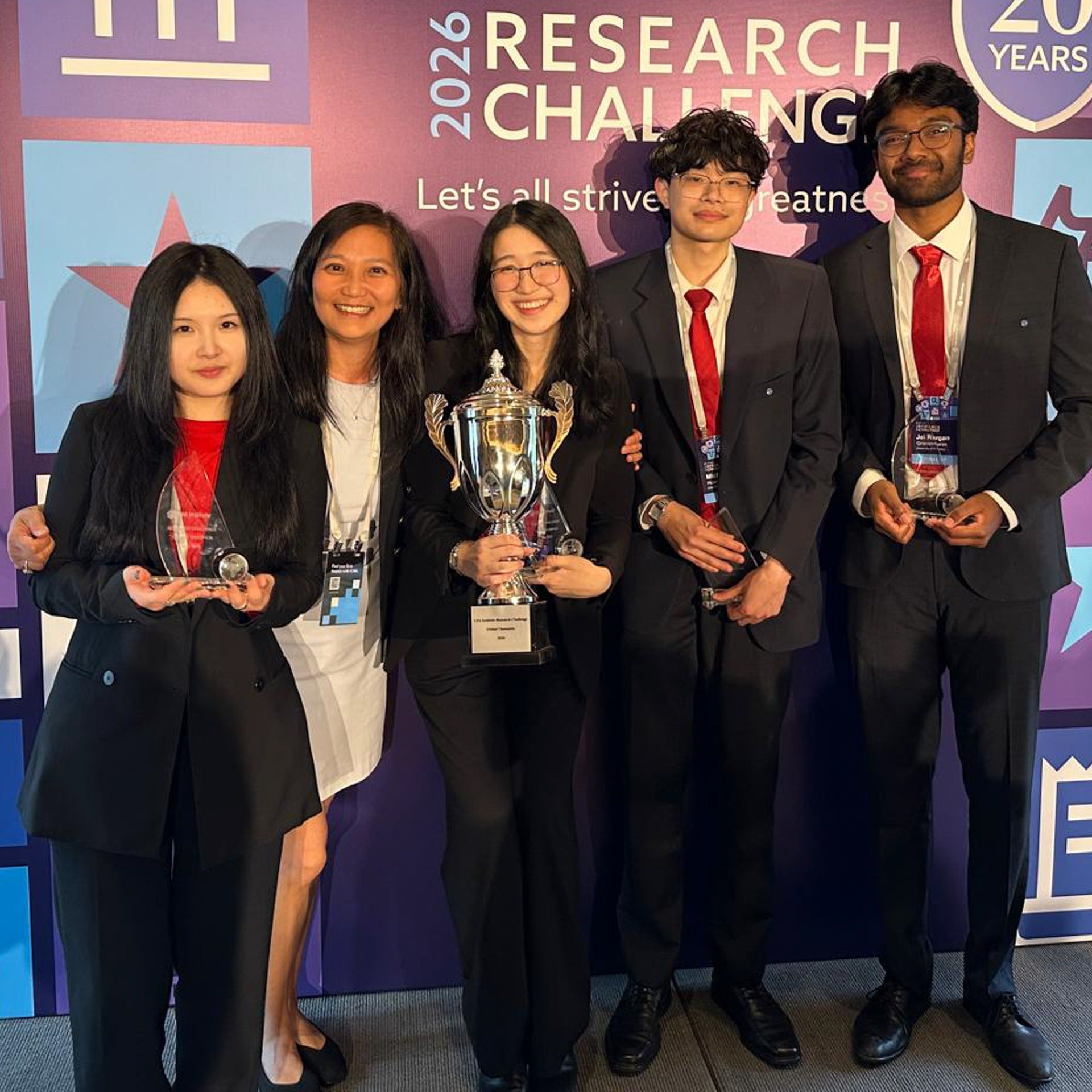 five young people holding trophies in front of CFA competition backdrop 