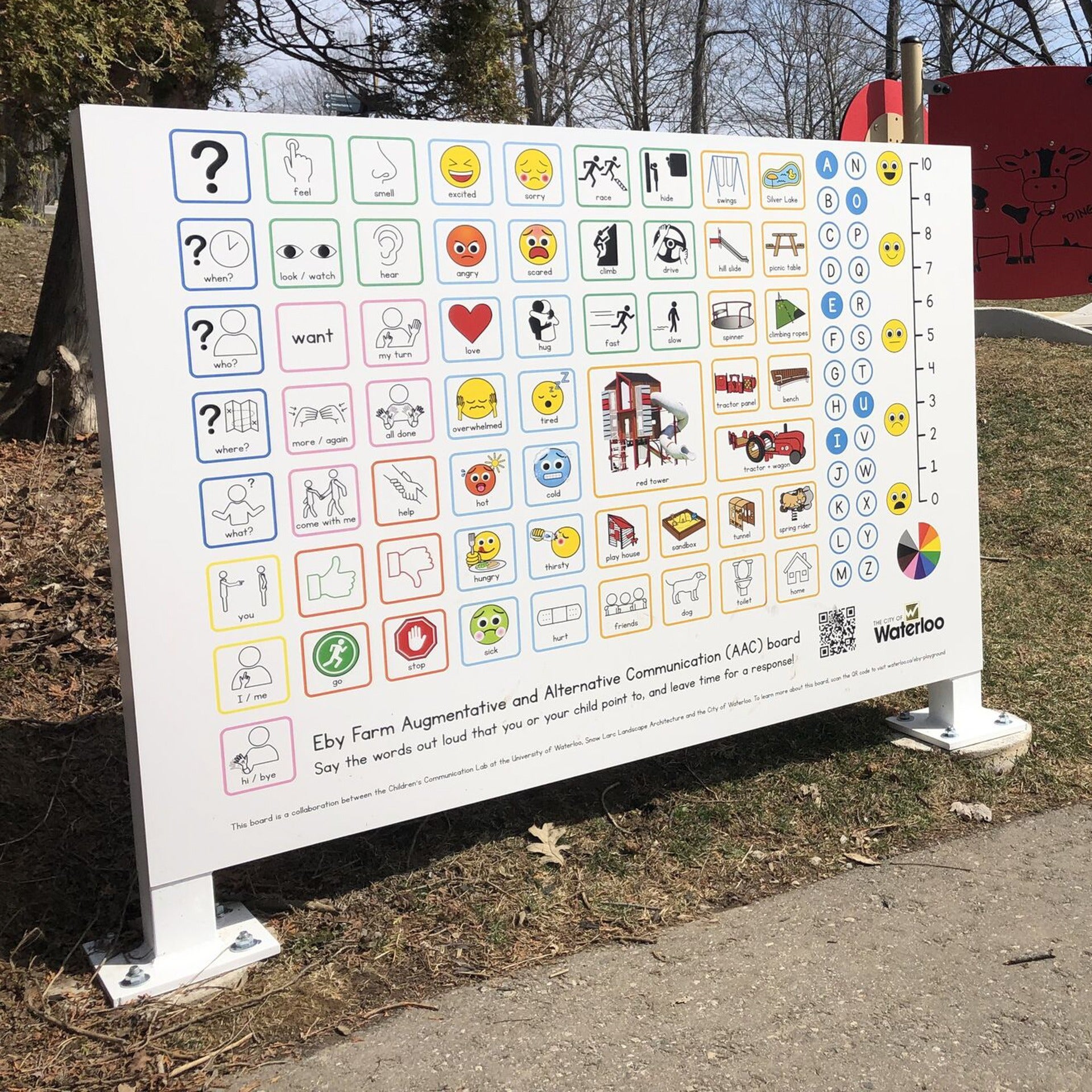 The alternative and augmented communication board near a path and playground structures. Content of the board described in story