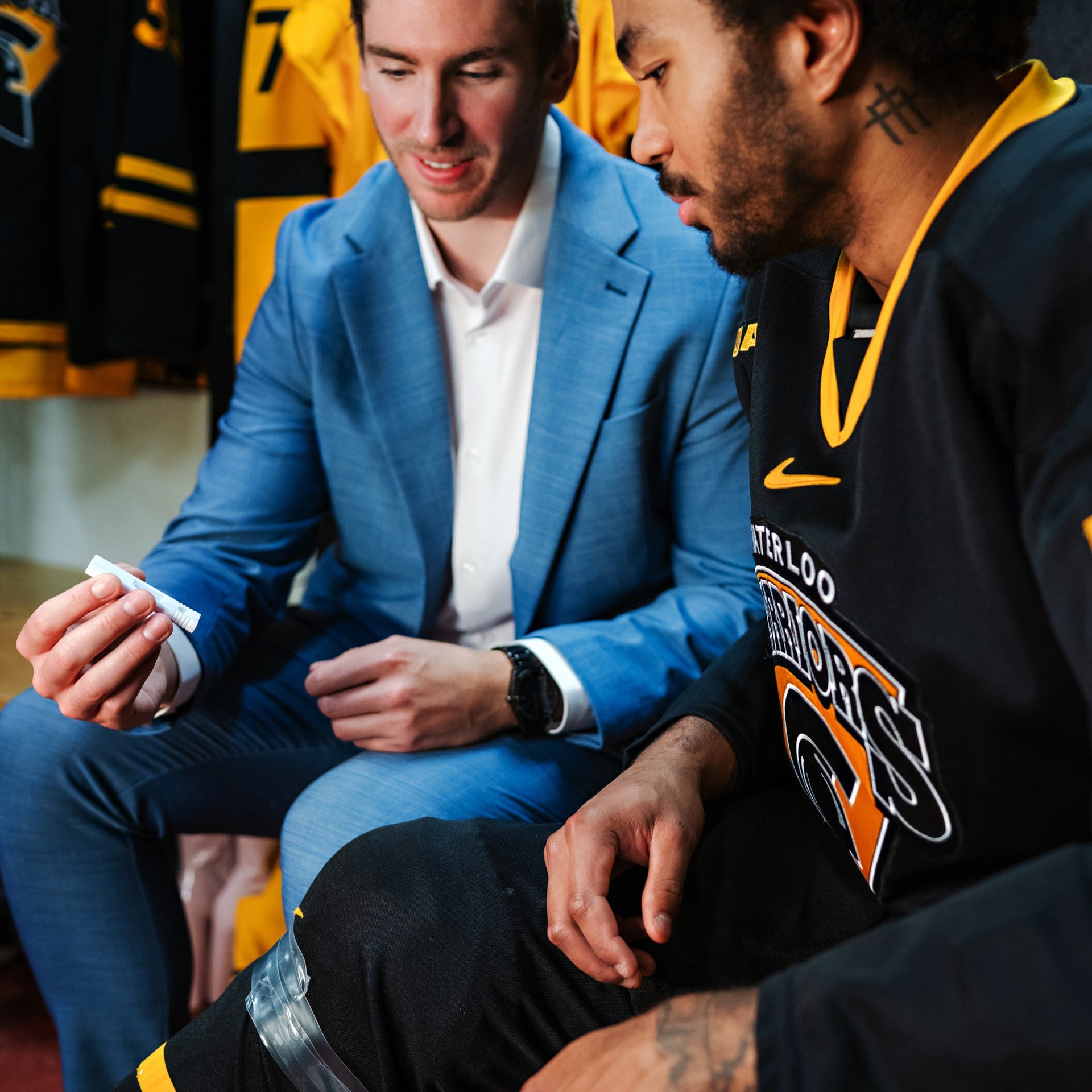 Andrew Cordssen-David holding a tester and showing a hockey player how to test saliva for a concussion
