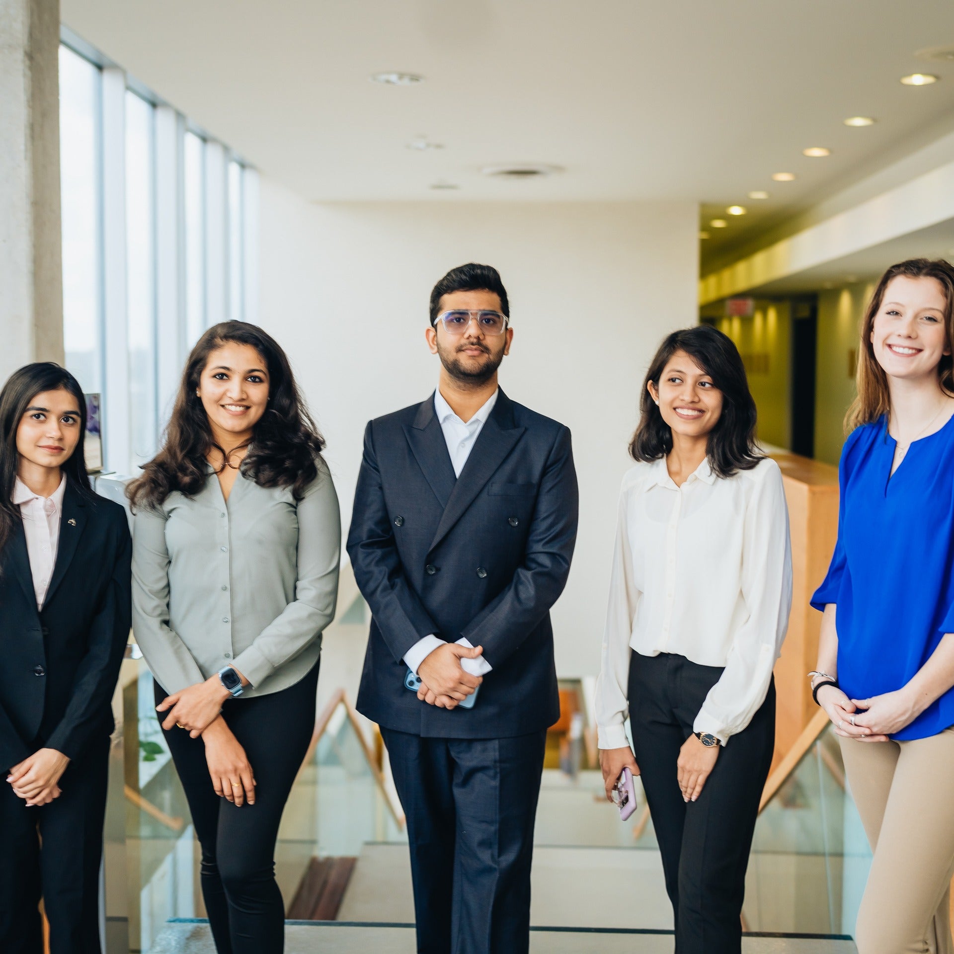 Waterloo co-op students wearing business attire inside the Tatham Centre and posing for a group photo