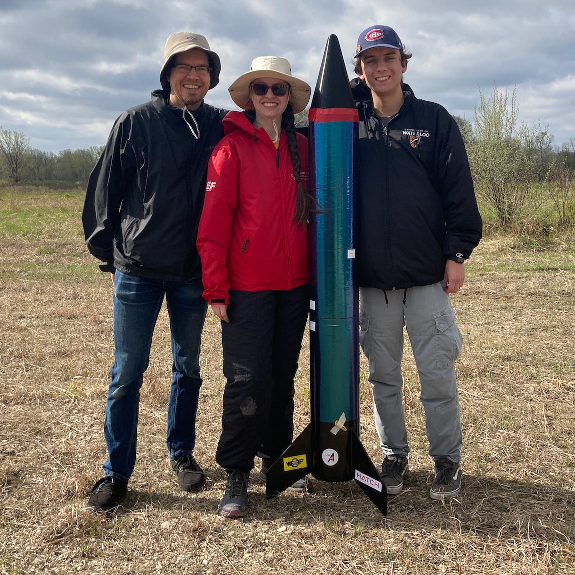 A team of five Indigenous students from the University of Waterloo standing beside a high-power rocket during the First Nations Launch competition