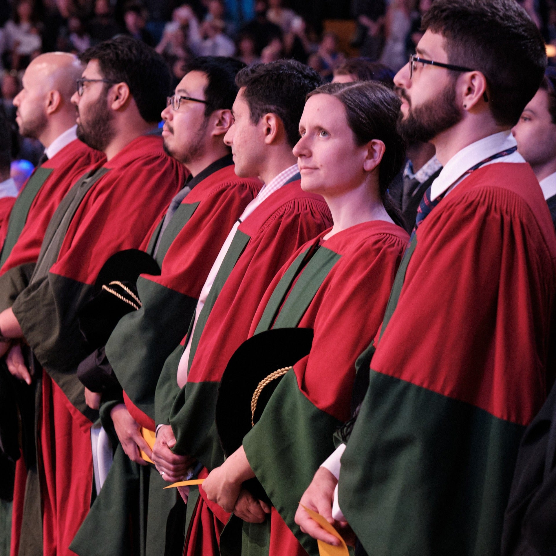 Front row of PhD graduates standing about to receive their doctorate degree