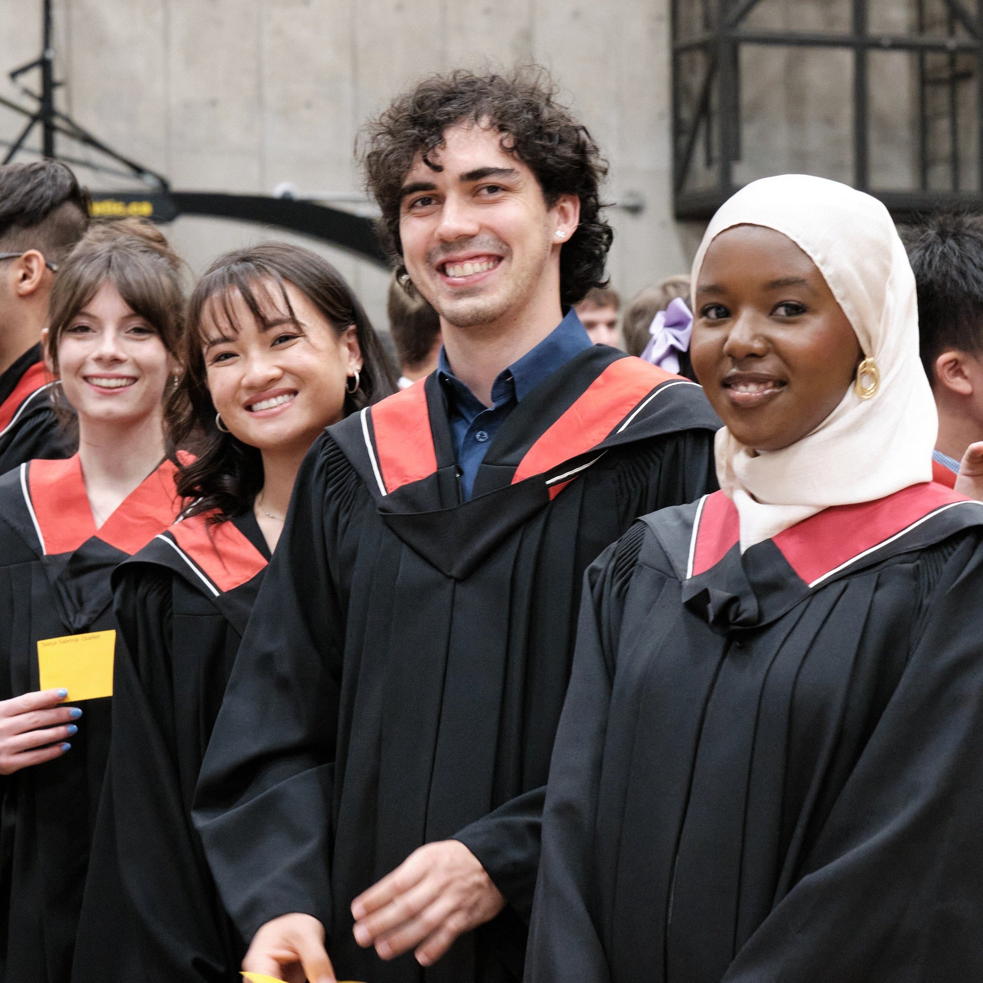 Spring 2024 graduates wearing convocation regalia waiting in line