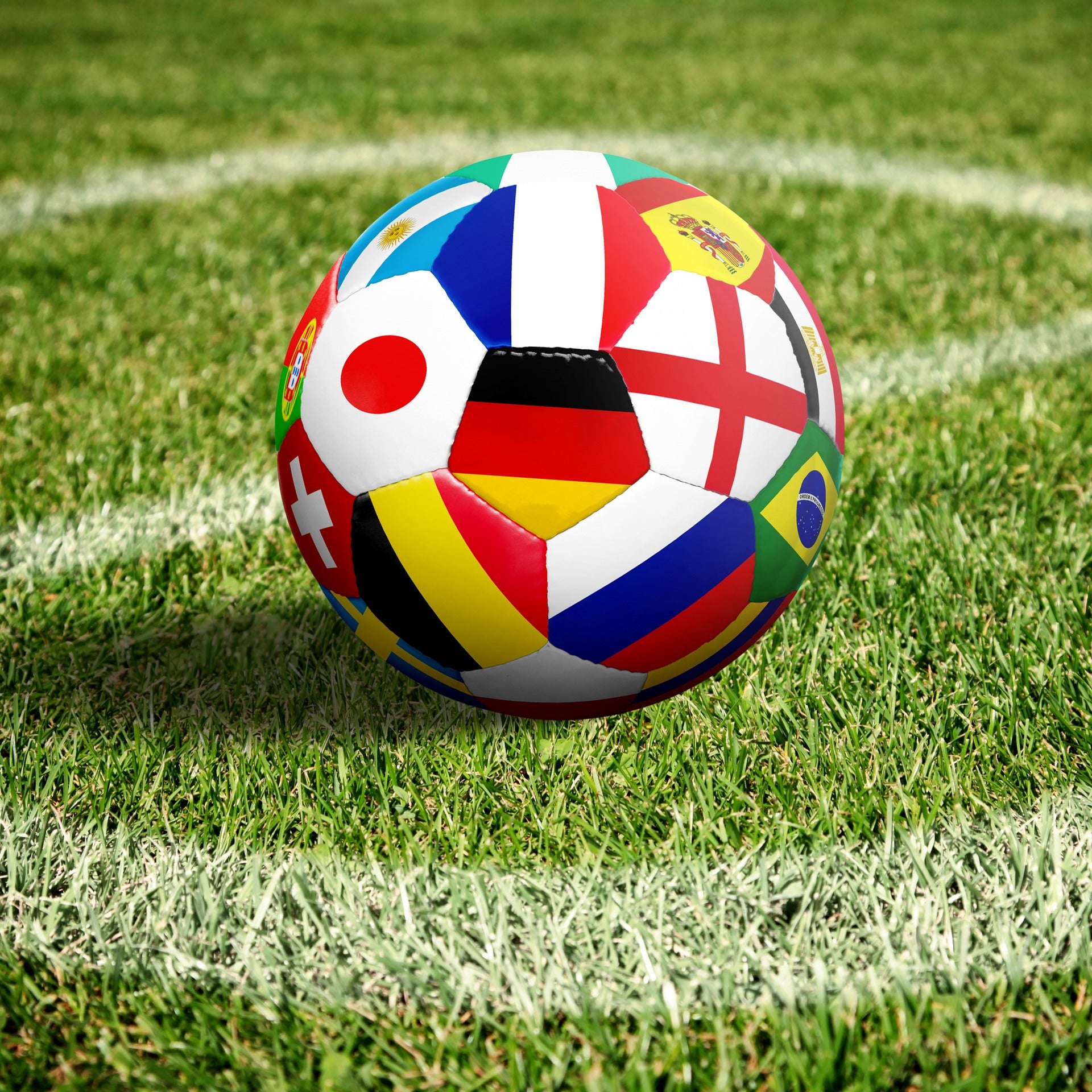 Soccer ball with country flags on a green field