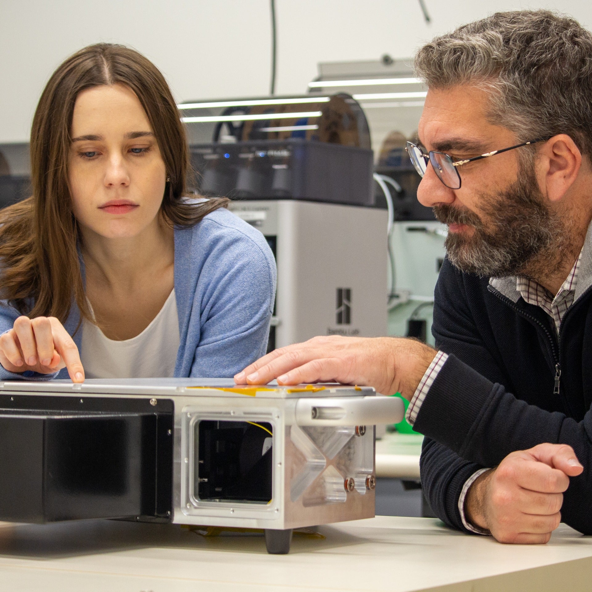 Alex Maierean showing co-founder a device inside a lab