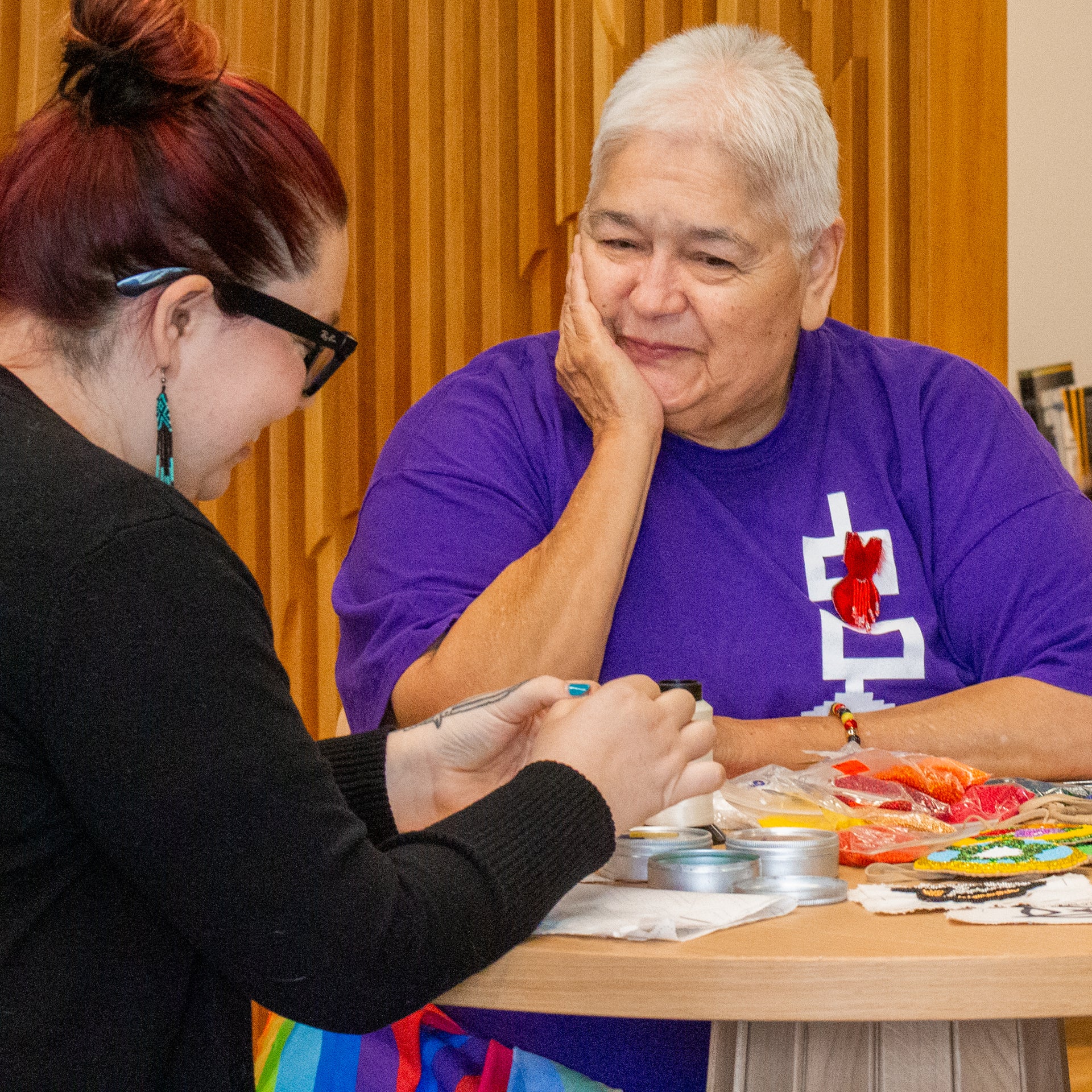 Rhea Green smiling with endearment watching Alissa Green do her own beadwork