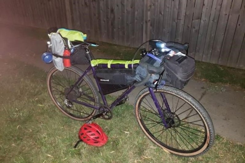 Picture of a bicycle parked at night with camping supplies strapped to it
